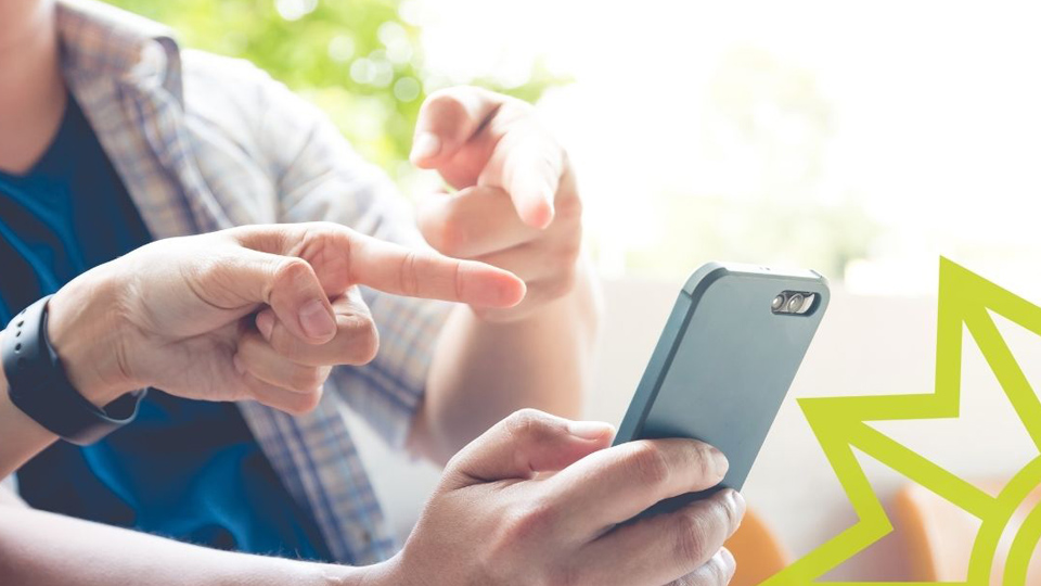 Nahaufnahme von einem Handy, auf das verschiedene Hände zeigen