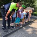 Polizist steht mit Kindern an der Borsteinkante 