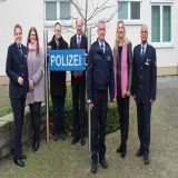 Personengruppe vor dem Polizeigebäude Oelde, aufgestellt um ein blaues Schild mit dem Aufdruck Polizei